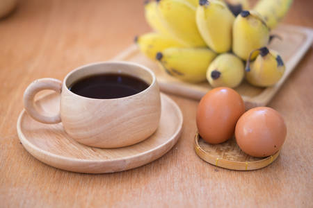 Breakfast set. Soft-boiled egg and banana with hot coffee on wood tableの写真素材