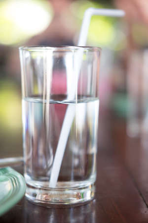 glass of water with straw on wood backgroundの写真素材