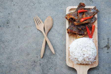 Thai cuisine curry fried Tilapia fish with spicy topping with riceの写真素材