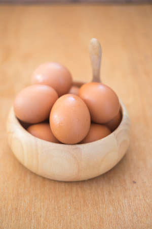 Fresh eggs in a wooden bowl on the tableの写真素材