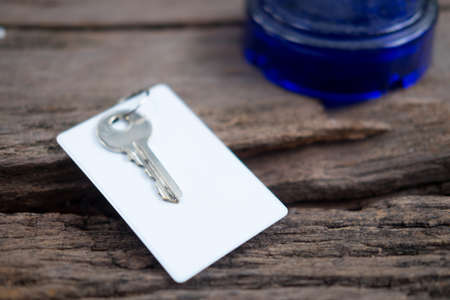 House key and keycard in keychain resting on wooden floorboardsの写真素材