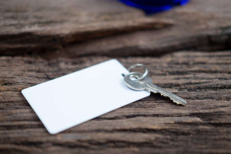 House key and keycard in keychain resting on wooden floorboardsの写真素材