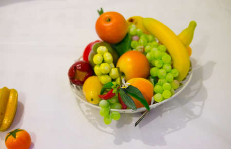 Artificial fruits in basket on white tableの写真素材