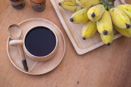 Hot of black coffee and banana on wood tableの写真素材