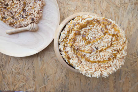 Thai sweet crispy rice cracker with cane sugar in wood bowl, one of traditional Thai sweet fried and pouring the sugar cane syrupの写真素材