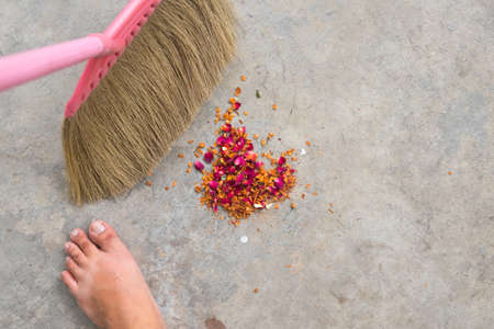 An unrecognizable person with a broom sweeping floor into dustpan.の写真素材