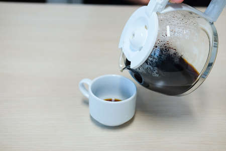 Close up of hand holding coffee maker while pouring coffee on cupの写真素材