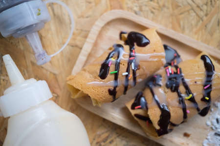 Kanom Tokyo topping with sauce chocolate and icing on wood tray, top viewの写真素材