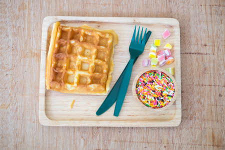 Waffle with topped fruit jelly candy and sugar sprinkle dots on wood trayの写真素材