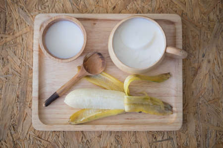 Soy milk dessert made of tofu with fresh banana on wood tray, healthy conceptの写真素材