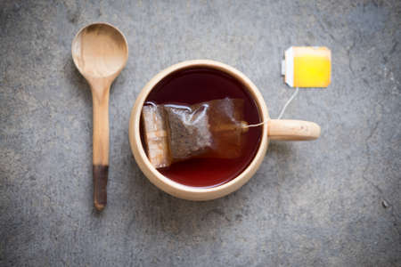 Hot tea with teabag in wooden cup and wooden spoonの写真素材