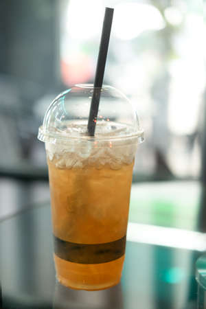 Ice lemon tea in takeaway glass on glass tableの写真素材
