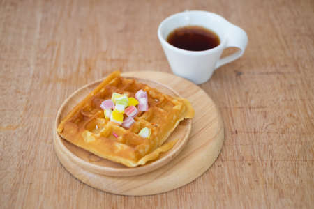 Homemade waffles and hot tea topping with jelly sweet on wood plateの写真素材