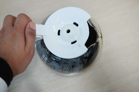 Hand keep hot coffee pot on wood table