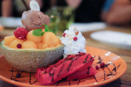 Ice cream with cantaloupe and waffle on orange plateの写真素材