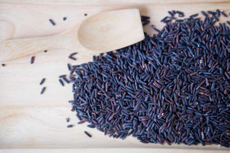 Black rice in wooden tray and wooden spoonの写真素材
