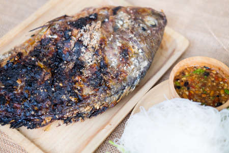 Grill salt Tilapia fish with rice noodles and spicy sauce on wood trayの写真素材