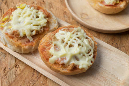 Fresh mini buns topped with pizza on wooden tray