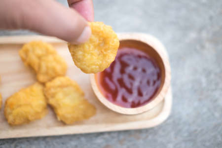 Man holding tasty nugget and bowl with sauce on table, selective focusの写真素材