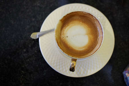 Hot coffee latte in white cup, top view