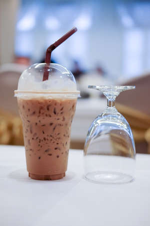 Cold coffee with ice in take away cup and glass of water in the conference roomの写真素材