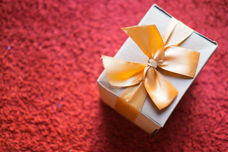 Brown gift box with golden ribbon on red backgroundの写真素材