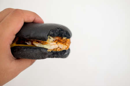 Eating black hamburger, black hamburger in man handの写真素材
