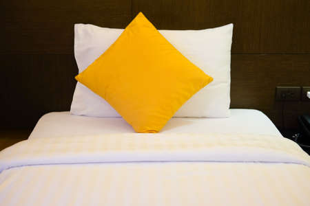 Yellow pillows on comfortable white bedの写真素材