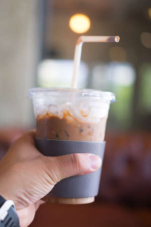 Iced cold mocha coffee with paper cup holder in young man handの写真素材