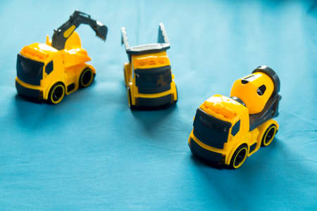 Three yellow toy  Industrial Vehicle on blue bed, Children's construction machineryの写真素材