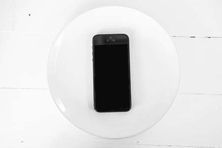 Top view smartphone on dish on wooden plank backgroundの写真素材