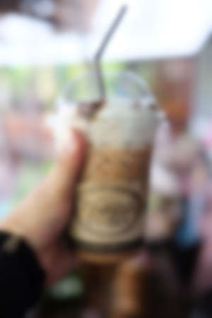 Blur background hand holding cup of ice coffeeの写真素材