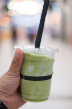 Green tea frappe and blended in young hand manの写真素材