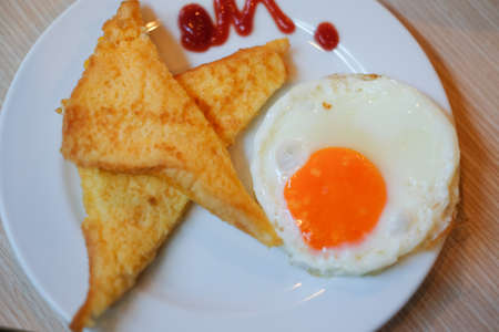 Fried eggs with toasts on white dish, top viewの写真素材