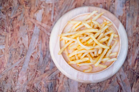 French fries in the wood plate on wooden table
