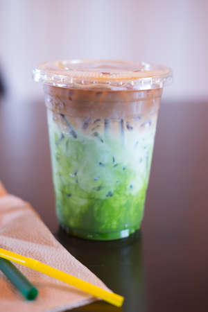 Ice coffee fusion three layer (espresso,milk and Matcha green tea) on wood tableの写真素材