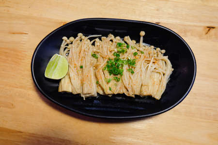 Enoki with lemon on black dish. Japan food style.