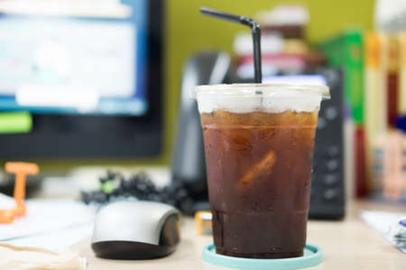 Plastic cup of iced black coffee Americano on desk at officeの写真素材