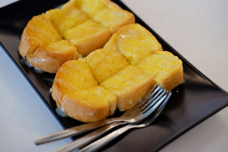 Buttered toast with sweetened condensed milk slice serving on black dishの写真素材