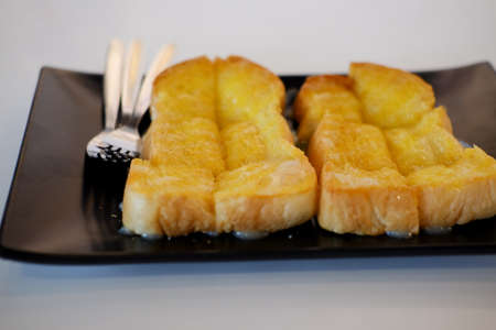 Buttered toast with sweetened condensed milk slice serving on black dish