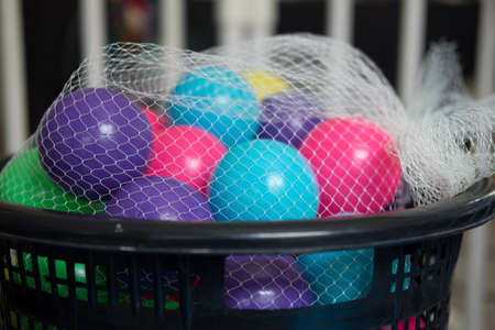 Colorful toy balls in mesh bag on black basketの写真素材