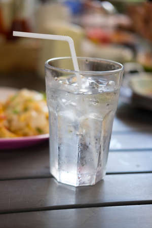 A glass of ice on brown wood table.の写真素材