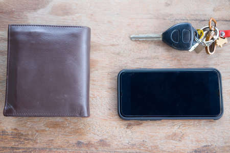 Car key, wallet and  smartphone on wood background, flat lay top view backgroundの写真素材