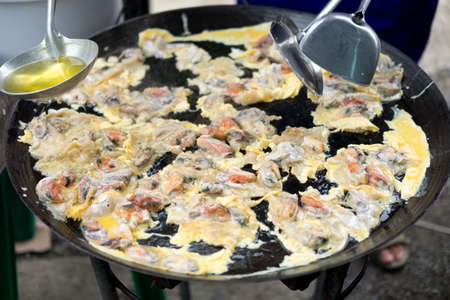 Cooking fried oyster omelet in big hot pan. Street restaurant in Thailandの写真素材