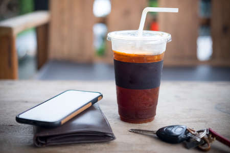 Ice of americano or black coffee with men wallet and car key on wooden table