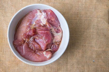 Raw pork meat slices in white bowl ready to cookの写真素材