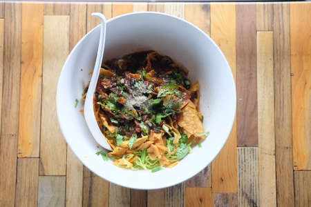 Thai noodle no soup serve with pork ball and toppings with dumpling on big white bowl