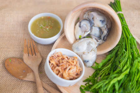 Fresh oysters in Thai style with chili paste seafood sauce and deep fried red onionの写真素材