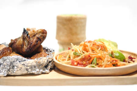 Grilled chicken and papaya salad on wooden plate (selective focus)