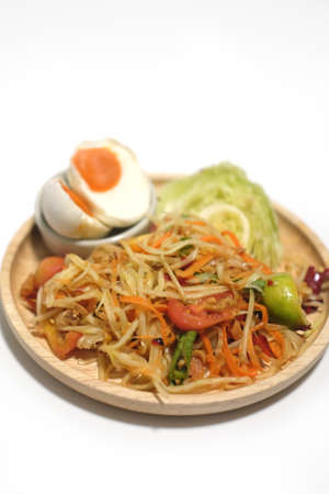 Thai Style Papaya Salad with Satled Eggs on wood dish on white backgroundの写真素材